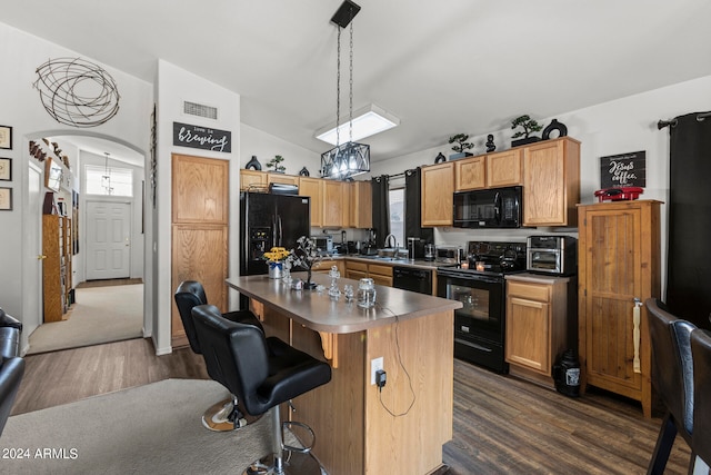 kitchen with decorative light fixtures, black appliances, a center island, dark wood-type flooring, and lofted ceiling