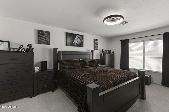 bedroom featuring visible vents, light colored carpet, and a textured ceiling