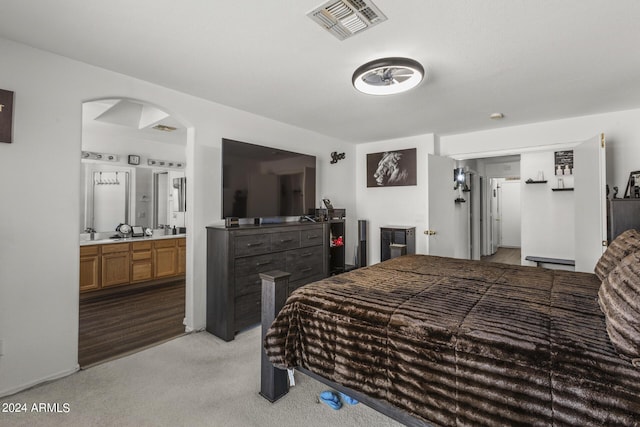 bedroom featuring visible vents, arched walkways, light colored carpet, and connected bathroom