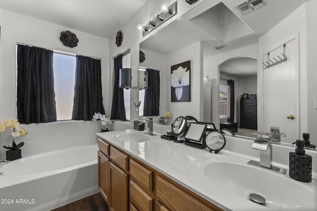 bathroom featuring a garden tub, double vanity, visible vents, and a sink