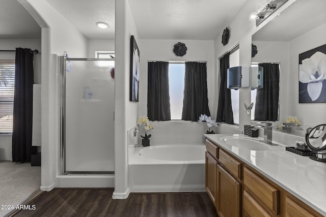 bathroom featuring a stall shower, vanity, a garden tub, and wood finished floors