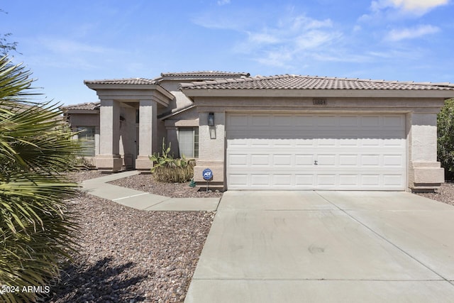 view of front of home with a tiled roof, stucco siding, an attached garage, and concrete driveway