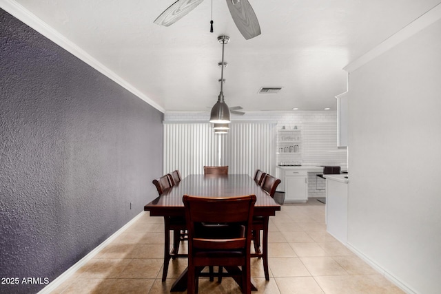 dining area featuring ornamental molding, visible vents, a textured wall, and light tile patterned floors