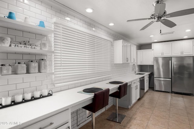 kitchen with light tile patterned floors, stainless steel appliances, a sink, white cabinets, and tasteful backsplash