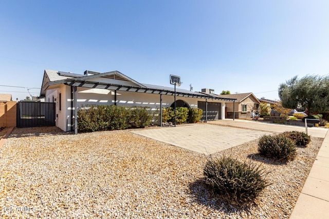 single story home featuring a garage, a gate, fence, decorative driveway, and roof mounted solar panels