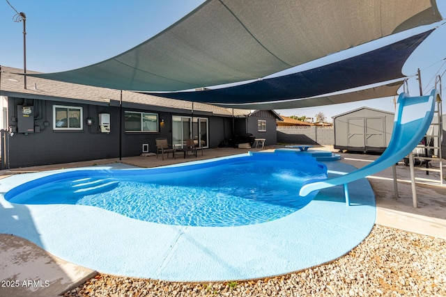 outdoor pool featuring a patio, an outbuilding, fence, a water slide, and a shed