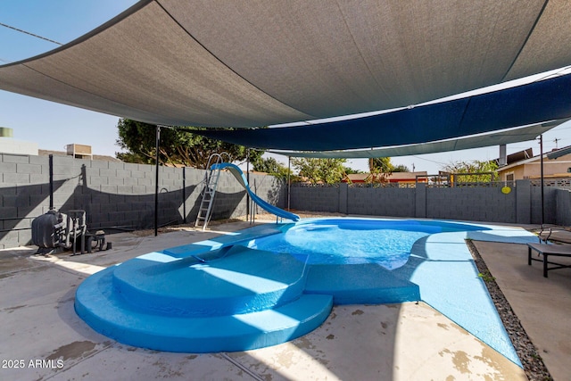 view of swimming pool with a water slide, a patio area, and a fenced backyard