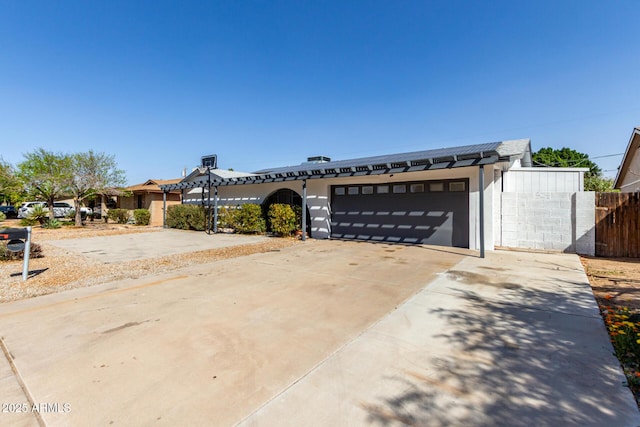 view of front of property featuring concrete driveway, fence, and an attached garage