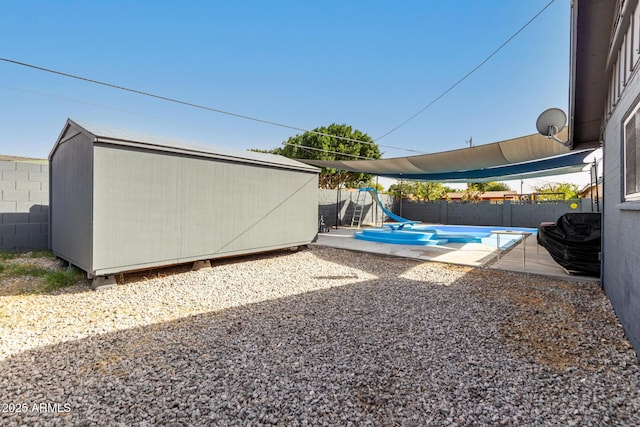 view of yard with a fenced in pool, a storage unit, a patio area, a fenced backyard, and an outdoor structure