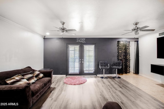 living area featuring baseboards, a ceiling fan, crown molding, and french doors