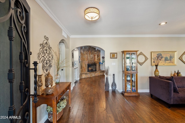 entryway featuring a stone fireplace, ornamental molding, and dark wood-type flooring