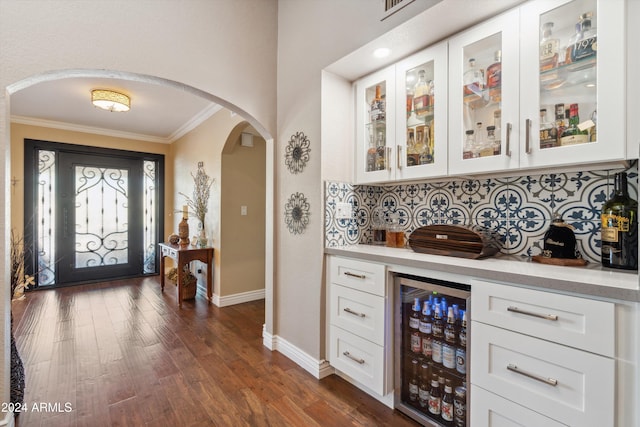 bar with dark hardwood / wood-style floors, wine cooler, ornamental molding, white cabinetry, and tasteful backsplash