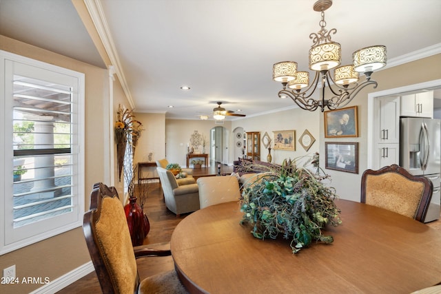 dining space with ornamental molding, ceiling fan with notable chandelier, and hardwood / wood-style floors