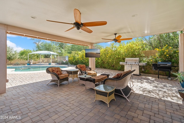 view of patio featuring area for grilling, ceiling fan, a fenced in pool, and exterior kitchen