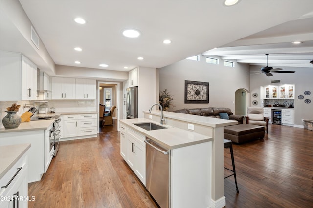 kitchen featuring vaulted ceiling with beams, hardwood / wood-style flooring, sink, white cabinetry, and appliances with stainless steel finishes