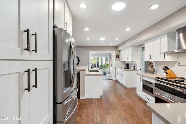 kitchen featuring light hardwood / wood-style flooring, white cabinets, tasteful backsplash, and stainless steel appliances