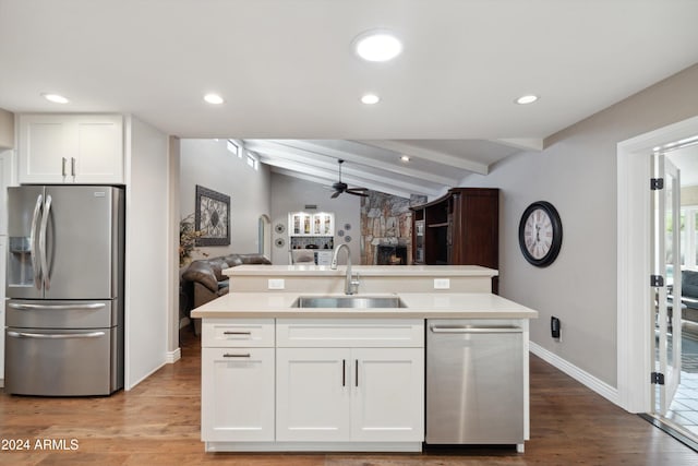 kitchen featuring appliances with stainless steel finishes, white cabinetry, light hardwood / wood-style flooring, lofted ceiling with beams, and sink