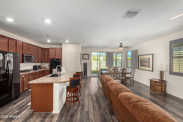 kitchen with black appliances, sink, dark hardwood / wood-style flooring, and an island with sink