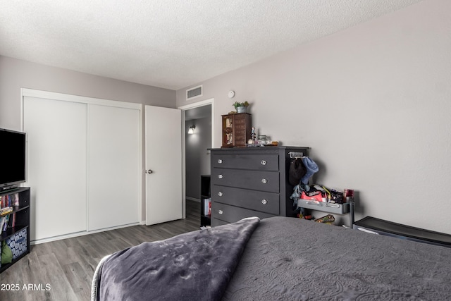 4240 N 67th Ln, Phoenix, AZ 85033 - bedroom featuring a textured ceiling, wood finished floors, visible vents, and a closet