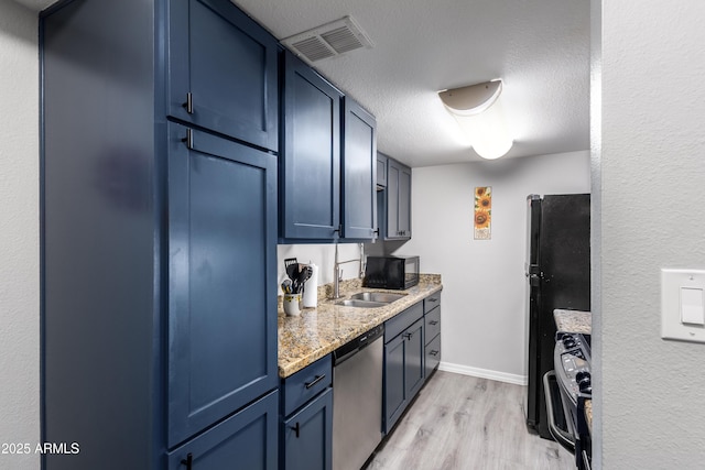 4240 N 67th Ln, Phoenix, AZ 85033 - kitchen featuring light wood finished floors, stainless steel appliances, a sink, a textured ceiling, and visible vents