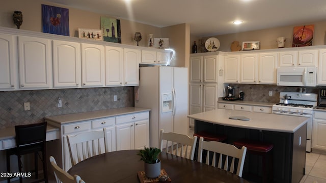 kitchen with a center island, white cabinetry, and white appliances