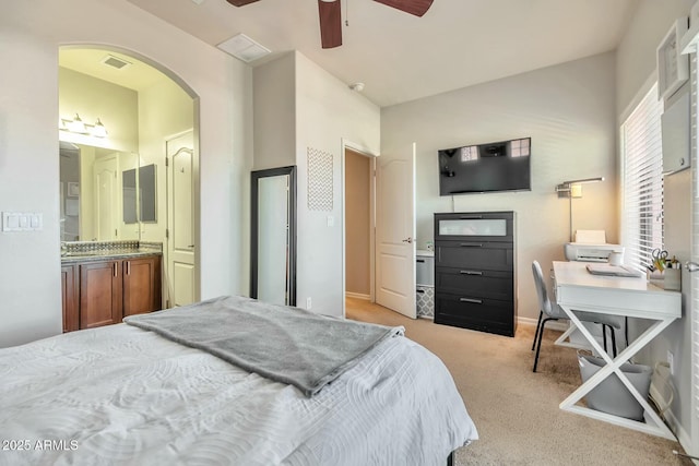 bedroom featuring visible vents, arched walkways, ceiling fan, light carpet, and connected bathroom