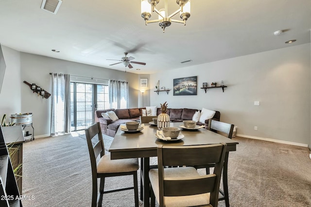 carpeted dining space featuring ceiling fan with notable chandelier, baseboards, and visible vents