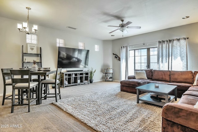 carpeted living room with visible vents, ceiling fan with notable chandelier, and baseboards