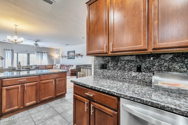 kitchen with dark stone countertops, tasteful backsplash, stainless steel dishwasher, open floor plan, and light tile patterned floors