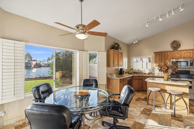 dining room with high vaulted ceiling, a water view, track lighting, and ceiling fan