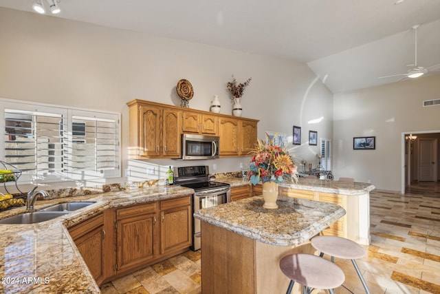 kitchen featuring a kitchen island, a breakfast bar, high vaulted ceiling, sink, and stainless steel appliances