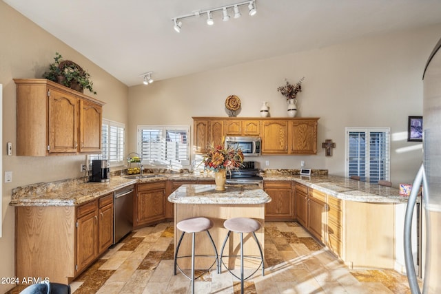 kitchen with sink, a breakfast bar area, stainless steel appliances, a center island, and kitchen peninsula