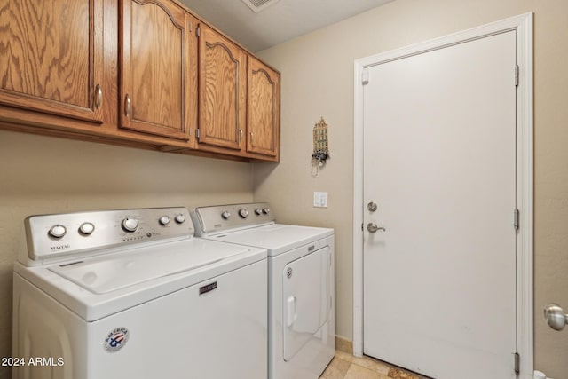 clothes washing area with cabinets and separate washer and dryer