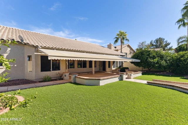 rear view of house with a patio and a lawn