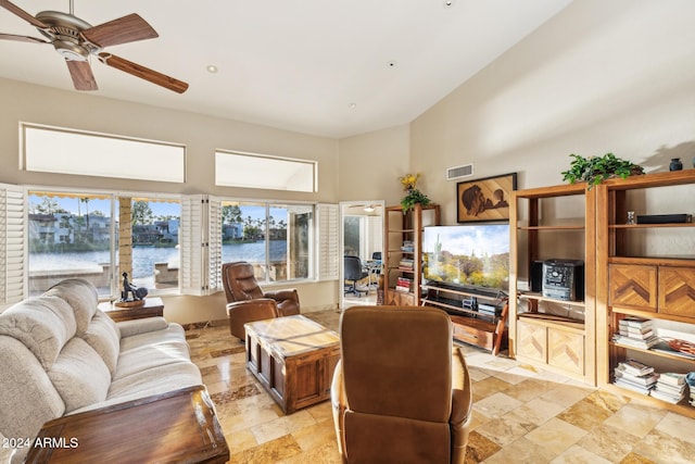 living room with ceiling fan, a towering ceiling, and a wealth of natural light