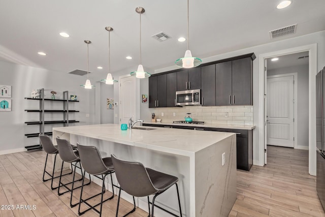 6931 W Spur Dr, Peoria, AZ 85383 - kitchen with a sink, appliances with stainless steel finishes, tasteful backsplash, light wood-type flooring, and recessed lighting