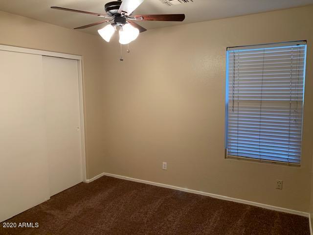 4533 E Glenhaven Dr, Phoenix, AZ 85048 - unfurnished bedroom featuring dark carpet, a closet, ceiling fan, and baseboards