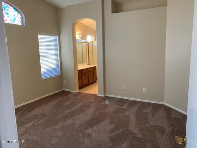 4533 E Glenhaven Dr, Phoenix, AZ 85048 - unfurnished bedroom featuring arched walkways, light colored carpet, baseboards, and ensuite bath