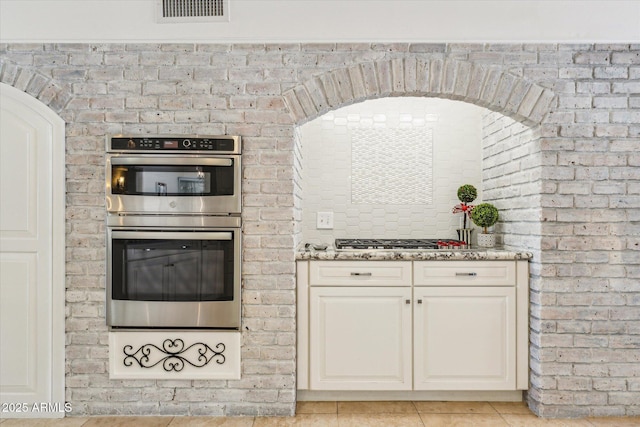 14401 N Coral Gables Dr, Phoenix, AZ 85023 - kitchen featuring light tile patterned floors, light stone counters, double oven, and visible vents
