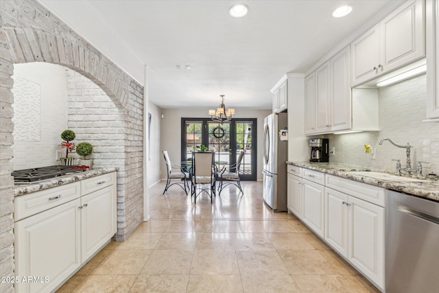 14401 N Coral Gables Dr, Phoenix, AZ 85023 - kitchen with decorative backsplash, a chandelier, white cabinets, a sink, and appliances with stainless steel finishes