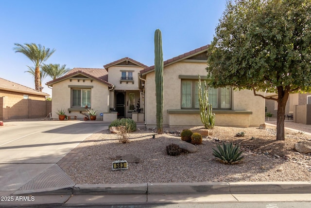 view of front of property featuring fence, a tile roof, and stucco siding