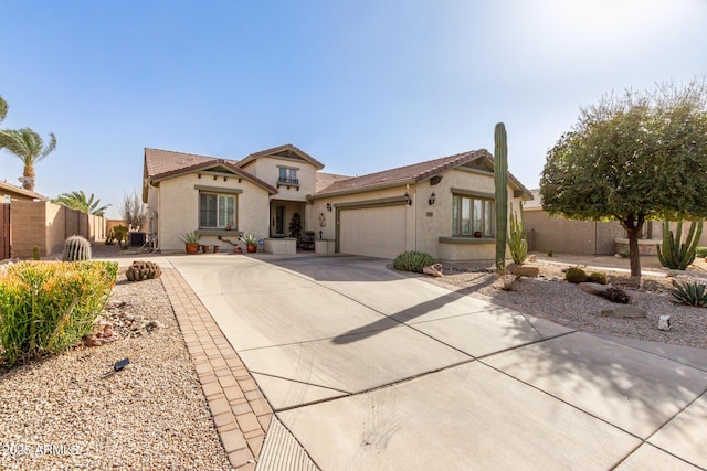 mediterranean / spanish-style house with a garage, concrete driveway, fence, and stucco siding