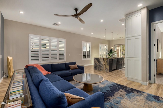 living room with ceiling fan, a healthy amount of sunlight, and light wood-type flooring