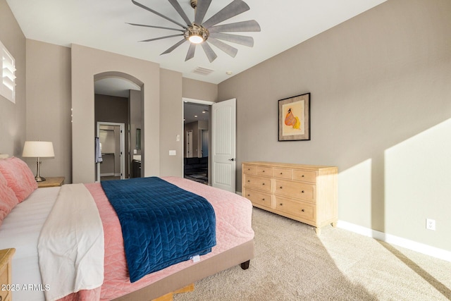 bedroom with ceiling fan, ensuite bathroom, and light carpet