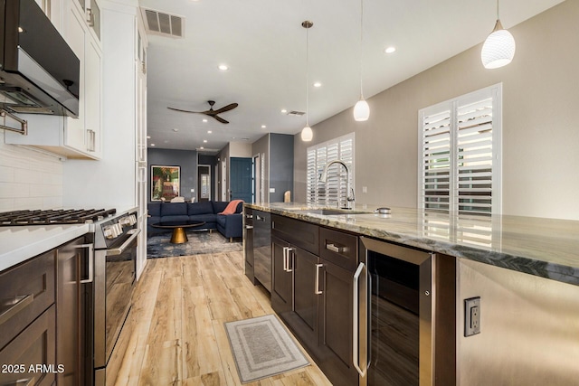 kitchen featuring pendant lighting, beverage cooler, white cabinets, and appliances with stainless steel finishes