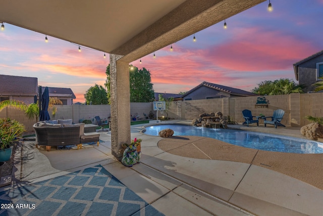 pool at dusk with a patio area, pool water feature, and an outdoor hangout area