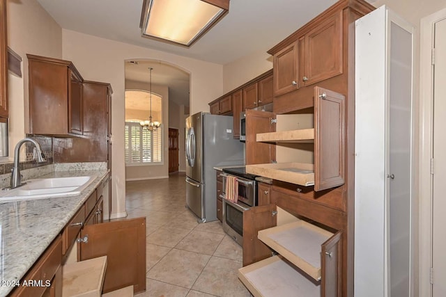 kitchen with pendant lighting, an inviting chandelier, sink, light tile patterned floors, and stainless steel refrigerator