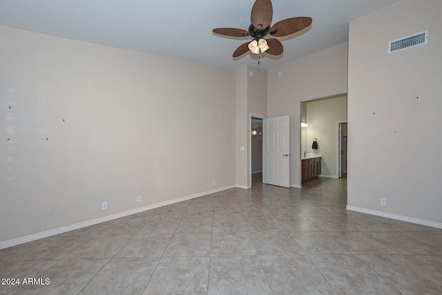 tiled empty room featuring ceiling fan and a towering ceiling