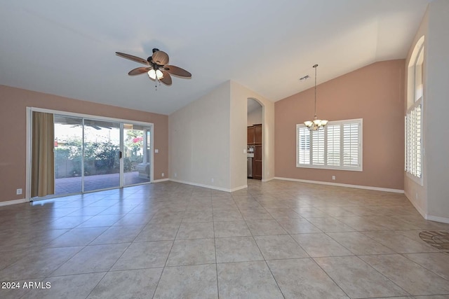 empty room featuring ceiling fan with notable chandelier, light tile patterned floors, and vaulted ceiling