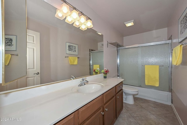 full bathroom with tile patterned flooring, vanity, bath / shower combo with glass door, and toilet